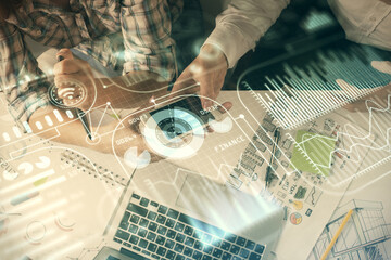 Double exposure of tech theme hologram and man and woman working together holding and using a...