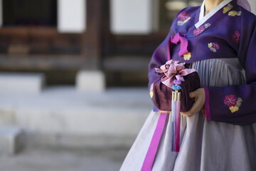 Naklejka premium Woman in Korean traditional clothes holding traditional package
