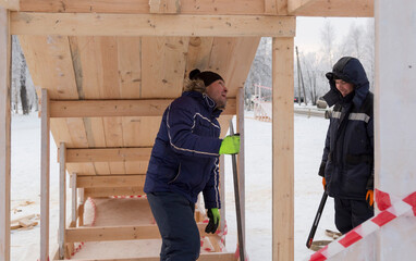 Fitter with a metal crowbar in hand at the construction of a wooden slide