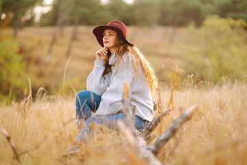 Stylish woman in sweater and hat enjoys autumn nature. People, freedom, lifestyle, travel and vacations concept.