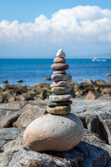 Fototapeta na wymiar Stack of stones near the sea with blue sea and white cloud background.