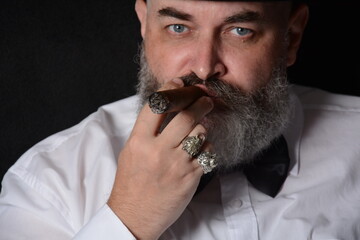 Portrait of a man with a cigar and a beard in a dark room