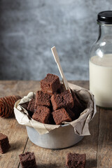 Chocolate brownie cake, dessert with milk on a dark background on a wooden table.