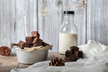 Chocolate brownie cake, dessert with milk on a dark background on a wooden table.