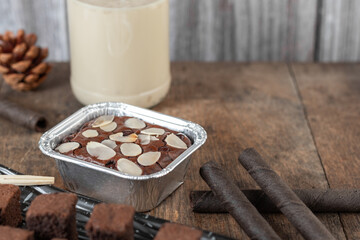 Chocolate brownie cake, dessert with milk on a dark background on a wooden table.