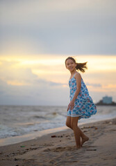 Silhouette of enjoying little girl on the beach, Kid relaxing in summer sunset sky outdoor