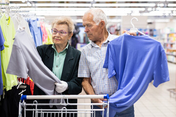 mature european couple chooses tee shirt in clothing department of supermarket