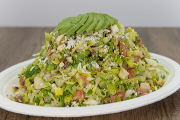 Avocado slices stacked on top of hugh cobb salad loaded with romaine and other healthy fixing for this meal
