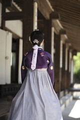 Woman in Korean traditional clothes standing at traditional Korean house
