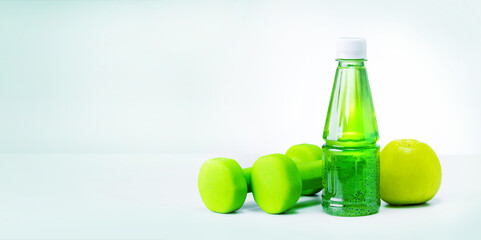 Green apple, bottle with natural juice and dumbbells. Banner with place for text.