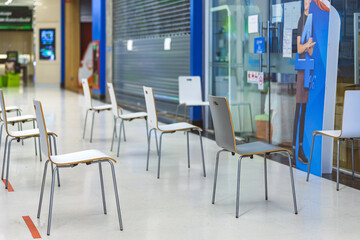 Group of empty chairs arranged for social distance in front of bank. COVID-19 health and safety measures during pandemic require spacing between people.Keep spaced between each chairs.Selective focus.