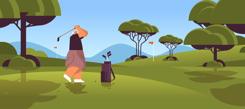 senior woman playing golf on green golf course aged player taking a shot active old age concept