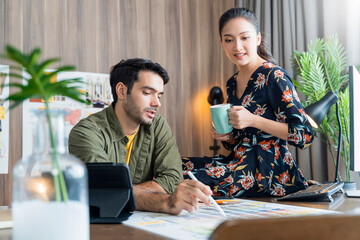 young asian and caucasian adult creative partnets working with new project discussion  brainstorm in office day time,meeting of designer partners conversation with focus and concentrate