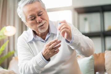 Old senior asian male hand nasal swab testing rapid tests by himself for detection of the SARS co-2 virus at home isolate quarantine concept