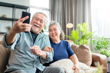 happiness asian old senior retired couple enjoy videocall to family together on sofa in living room...