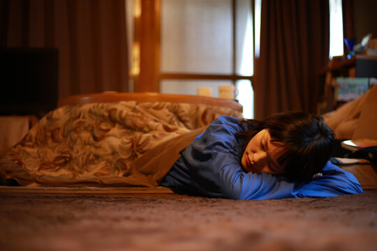 こたつで居眠りする女性
