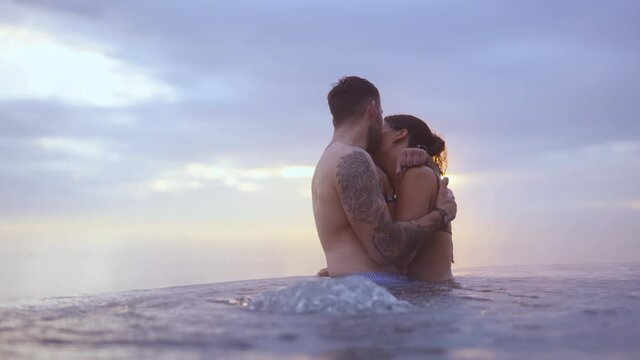 Couple Cuddling on an Infinity Pool in the Golden Sunset at Dusk