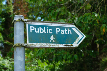 A green public walking path sign pointing to the right
