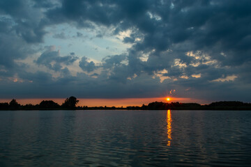 Fototapeta premium Dark clouds and sunset over the lake