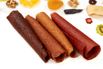 Close up of delicious juicy fruit lozenge of own production on table with tasty dried fruits orange, kiwi, apricot and bananas. Concept of healthy assorted dried fruit for snacks.