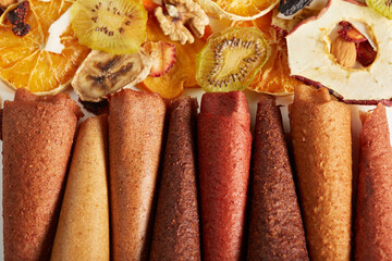 Close up of delicious juicy fruit and berries lozenge on dried fruits orange, kiwi, coconut, nuts background. Concept of healthy assorted dried fruit for snacks.