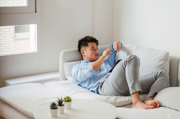 Fototapeta premium Young handsome Chinese man at home sitting on couch using digital tablet
