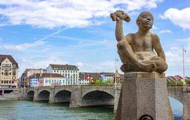 Fountain Knabe mit Fisch (boy with fish) close to Rhine river and Mittlere Brücke (middle bridge) in Basel city, Switzerland