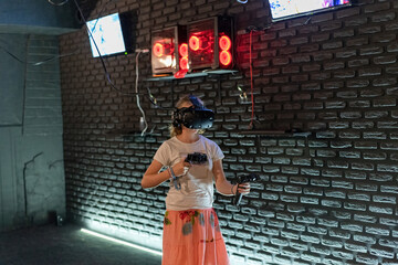 A girl in a VR helmet plays games in a computer club.