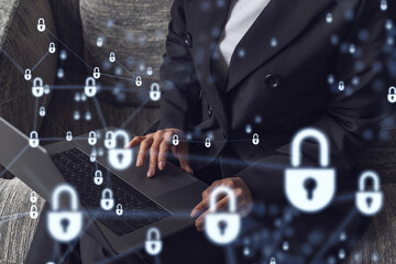 A woman programmer is typing a code on computer to protect a cyber security from hacker attacks and save clients confidential data. Padlock Hologram icons over the typing hands. Formal wear.