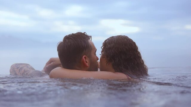 Couple Being Intimate While Bathing in Infinity Pool With View of Blue Heavens