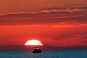 A small boat sets out to sea in the sunrise
