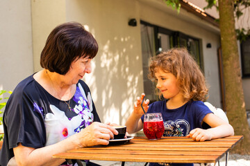 Little girl and her grandmother drink coffee and cocktail
