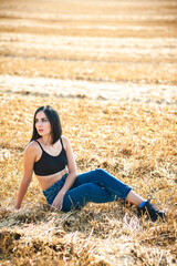 Naklejka na ściany i meble Beautiful woman model wearing summer cotton clothes posing in autumn field with hay stack. 