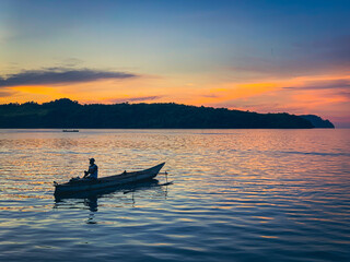 The silhouette of a fisherman on a boat during a beautiful sunset. Nature photography