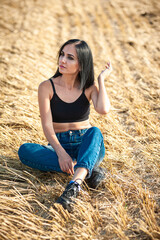 Naklejka na ściany i meble Beautiful woman model wearing summer cotton clothes posing in autumn field with hay stack. 