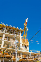 High-rise building under construction. The site with cranes against blue sky