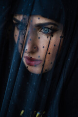  Muslim young woman on dark background wearing black hijab