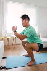 Young handsome Chinese man practicing yoga in the living room