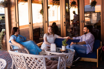 The happy friends are talking and laughing in a cafe terrace