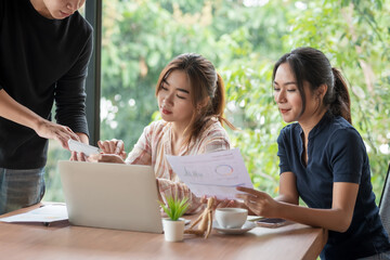 Team of young Asian business people are working together brainstorming discussing together using document and laptop placed at the office.