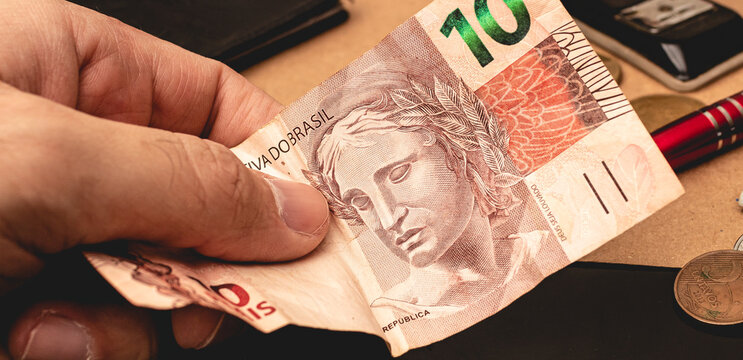 Dinheiro, Brasil, Real BRL. Um homem segurando uma c&eacute;dula do Real Brasileiro em foto de perto. Tempo de crise financeira com alta da infla&ccedil;&atilde;o no Brasil.