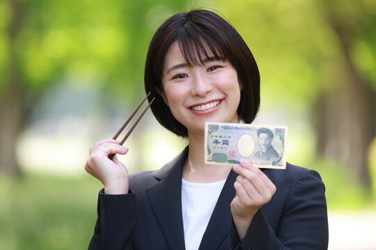 千円札と箸を持つ女性社員　千円ランチイメージ