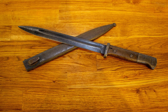 Top view of an old antique long sharp knife with its metal  case on the wooden floor