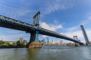 Manhattan Bridge crosses over the East River from the Brooklyn Bridge Park on June 20, 2021 in New York City, USA. Lower Manhattan skyscraper can be seen beyond the bridge.