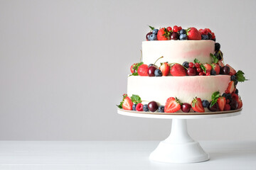 Two-tiered wedding cake in chocolate, with slices strawberries, raspberries, blackberry on a white...