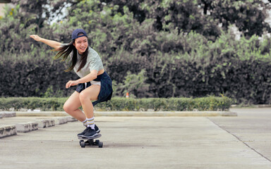 Portrait beautiful sportive Asian female skater wearing hipster shirt with shorts, smiling with happiness, standing on skateboard and playing outdoor with copy space. Activity and Adventure Concept. © Ann Rodchua