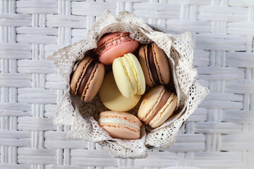 Multicolored macarons on white wicker table