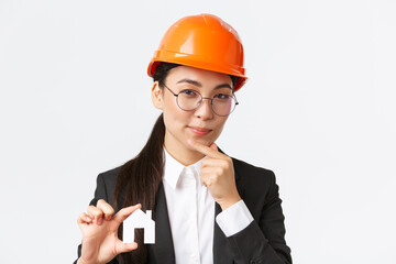 Thoughtful creative female asian architect in helmet and business suit creating new ideas of...