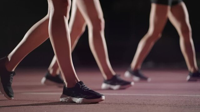 Close-up of the legs of women runners in sneakers in the dark near the start line, preparation and strat of the race