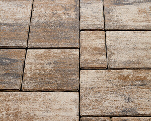 Paving design of street paths made of colored cement boulders of different shapes. Selective focus on the center of the composition.